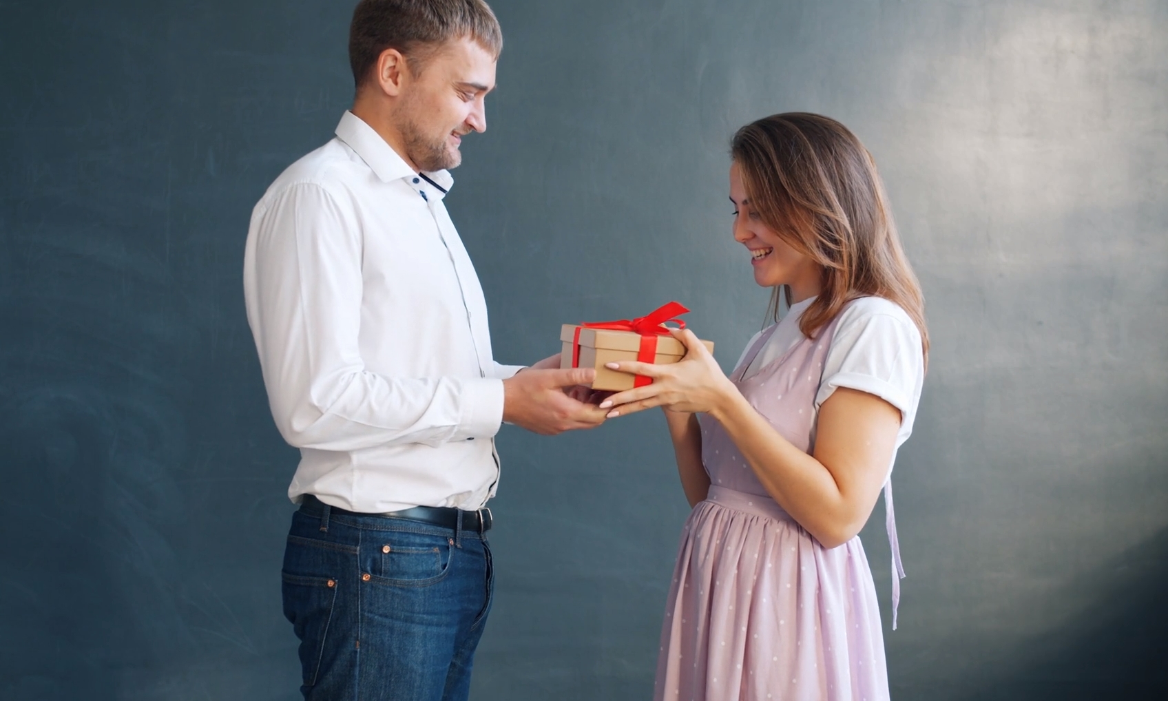 A man joyfully presents a gift to his girlfriend, expressing love and affection.