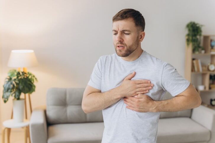Man touching his chest with a worried expression while experiencing rapid heartbeat and chest tightness during a panic attack