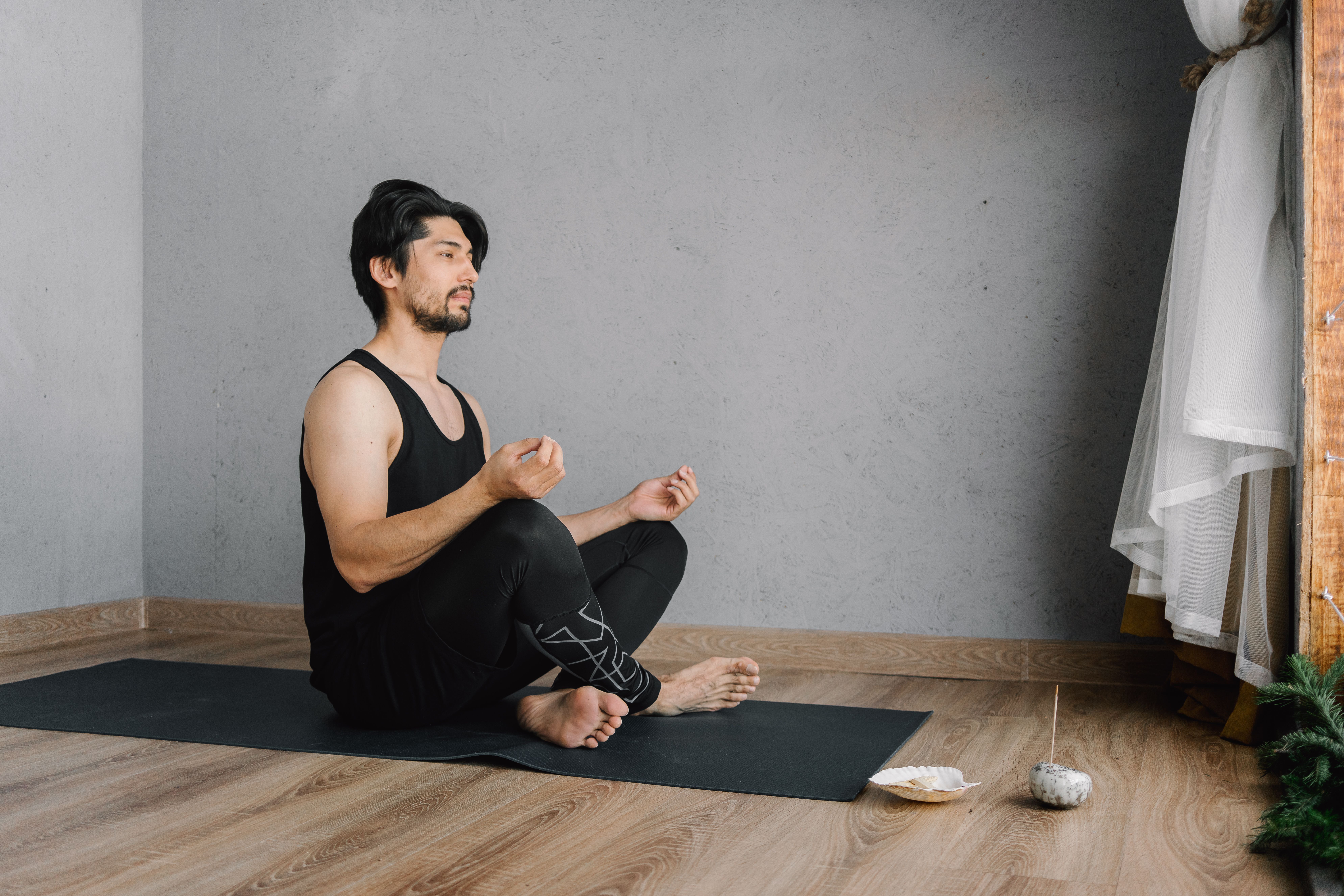 Man meditating on a yoga mat indoors as a mindfulness option for a mental health menu.