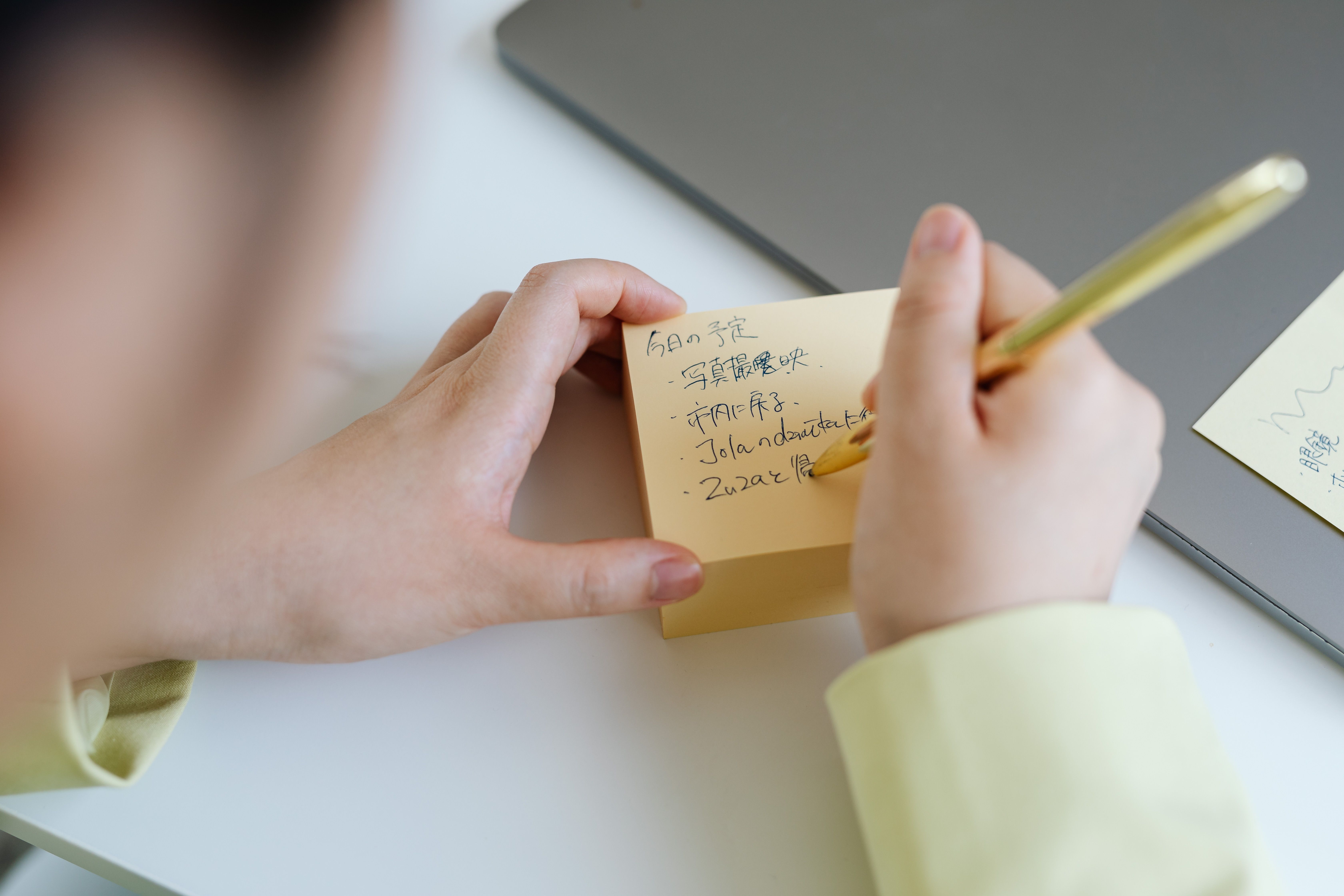 Person writing on a sticky note while planning personalized self-care activities.