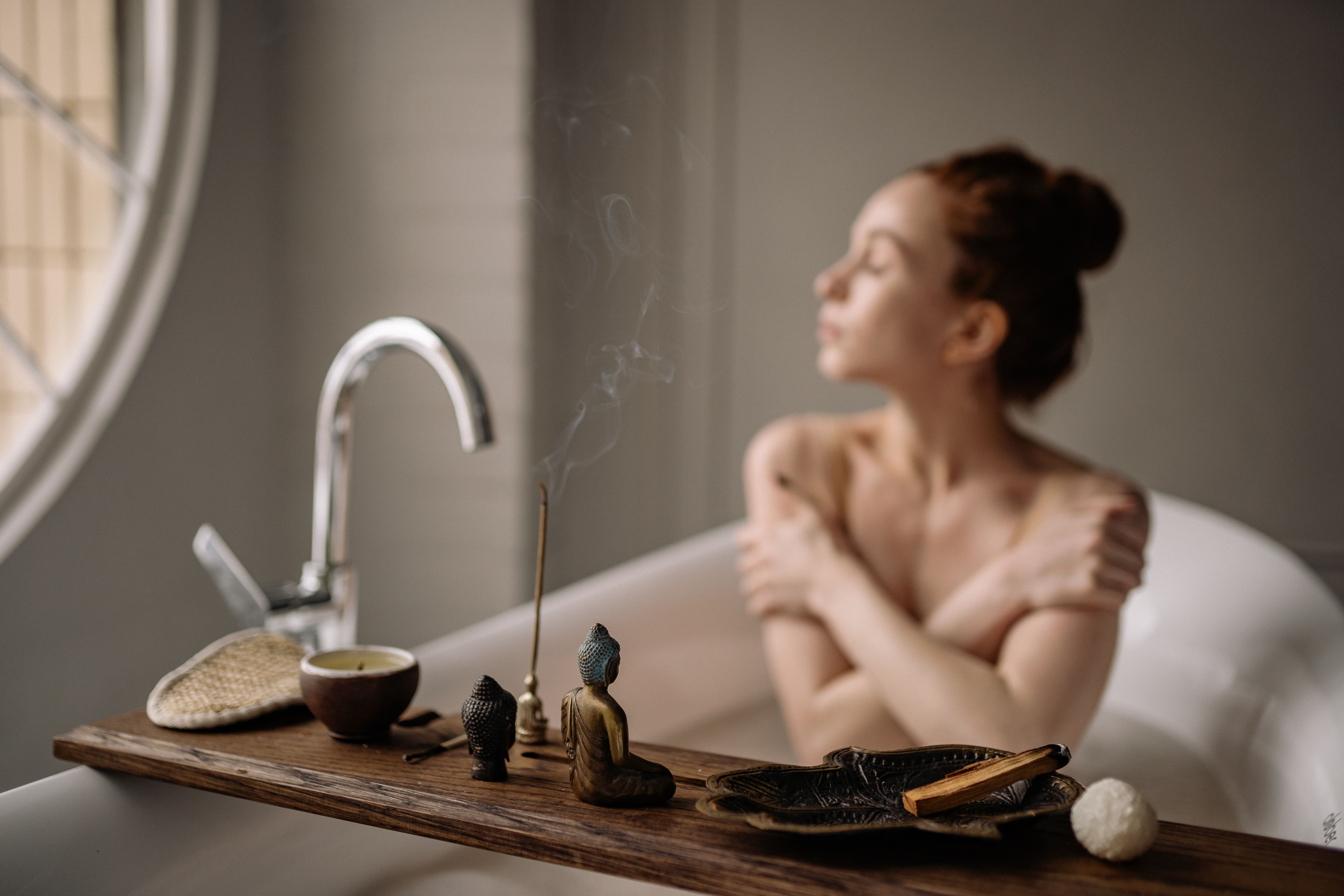 Woman enjoying a peaceful bath with tea and incense during a restorative self-care ritual.